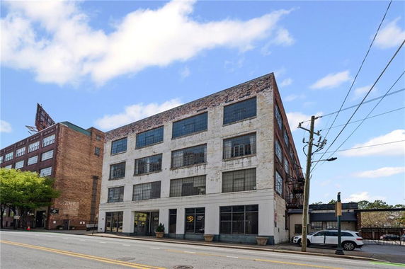 Front view of a multi-story industrial-style building with large windows.