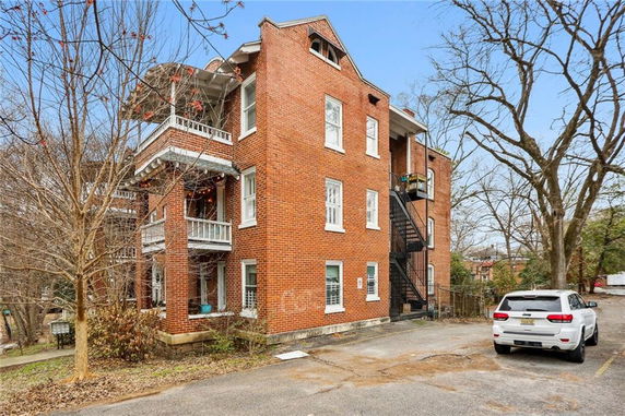 Front view of a multi-story brick building with balconies and external staircase.