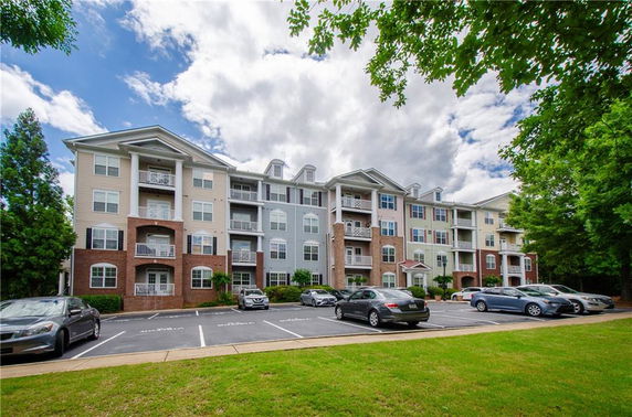Front view of a multi-story residential building with parking area in front.