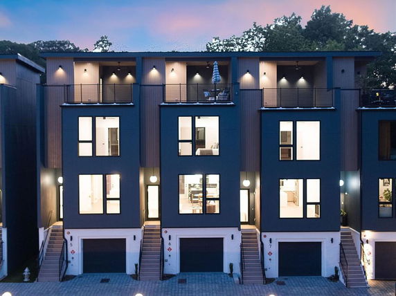 Front view of modern multi-story townhouses with large windows and balconies.