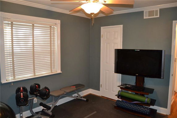 Room with exercise equipment, including weights, a bench, and a television.