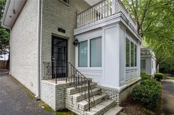 Front view of a brick house with stairs leading to a door.