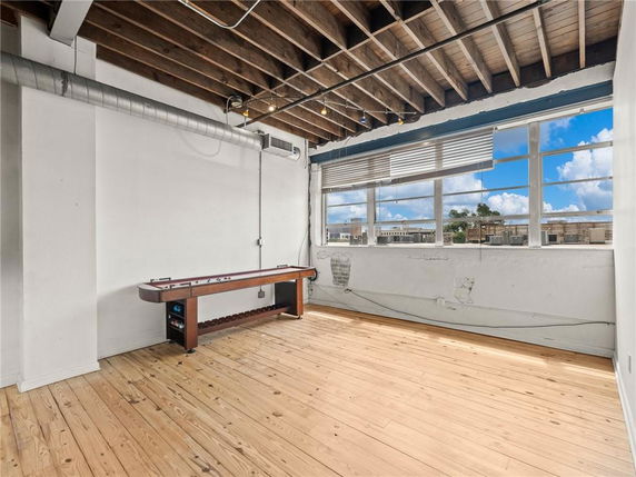 Room with wooden floors, large windows, and a shuffleboard table.