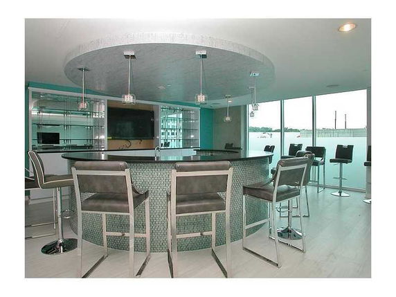 Interior view of a modern club house with a bar area and high chairs.