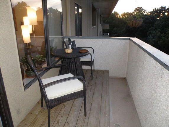 Balcony with outdoor seating and distant view of surrounding trees.