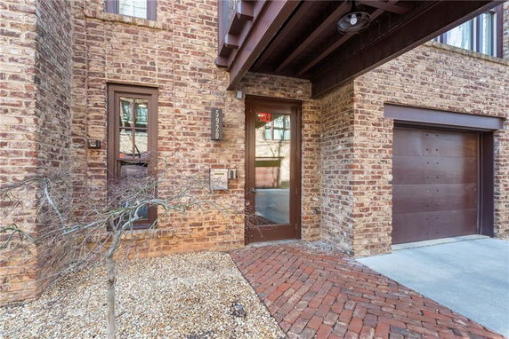 Front view of a brick house with a small tree and attached garage.