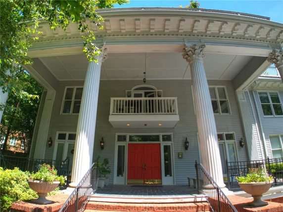 Front view of a two-story house with large columns and a red door.