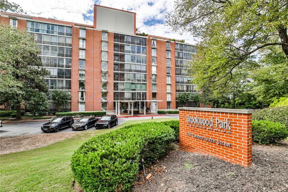 Front view of a multi-story condominium building with glass and brick facade, and an entrance area.