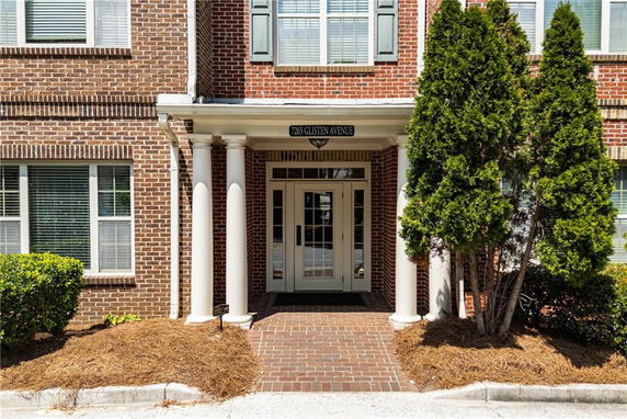 Front view of a brick building entrance with columns and windows.