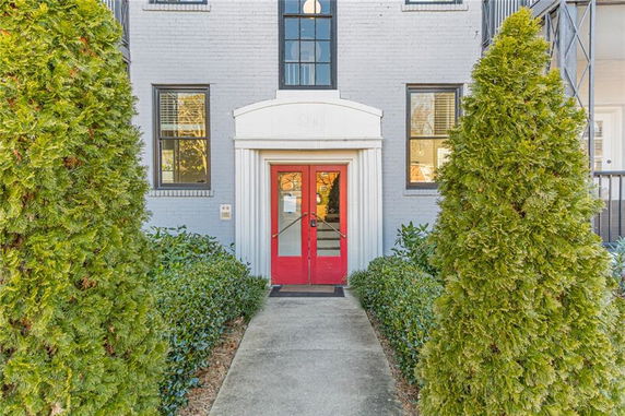 Front view of a brick building with a red door and white arch above the entrance.