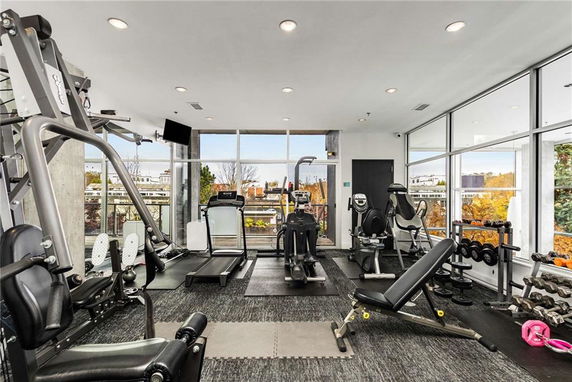 Gym area with various exercise equipment and large windows.