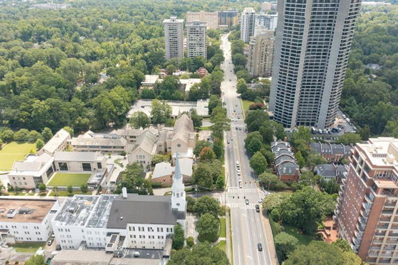 Aerial view of a cityscape with tall buildings, roads, and surrounding greenery.