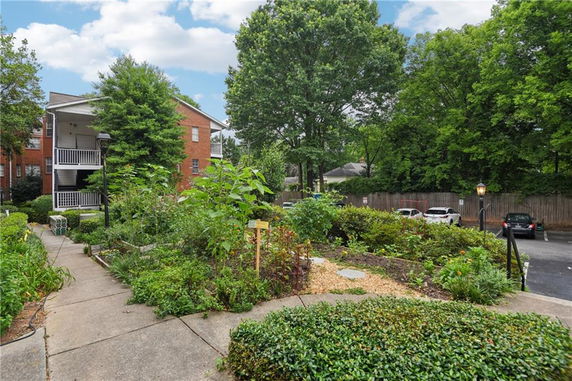 View of residential building with parking area and surrounding gardens.