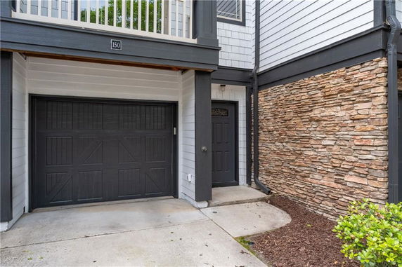 Front view of a house with a garage door and stone exterior accents.