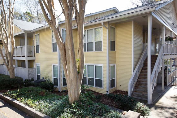 Front view of a two-story yellow house with an external staircase.