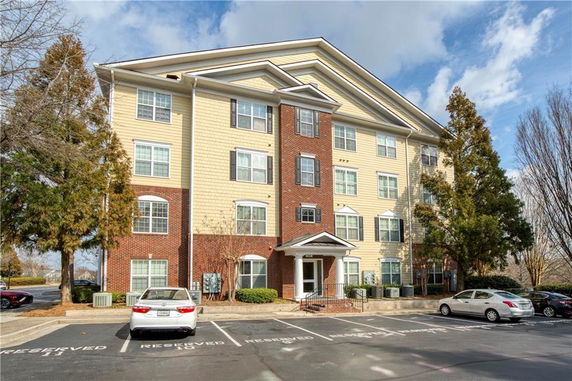 Front view of a four-story apartment building with reserved parking.