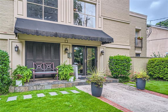 Front view of a house with bench and potted plants on a small porch.
