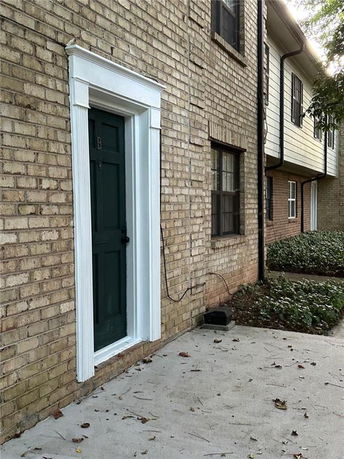 Front view of a brick building with a green door labeled B.
