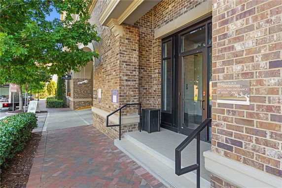 Front view of a brick building entrance with steps and a glass door.