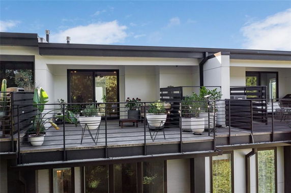 Front view of a house with a balcony and potted plants.
