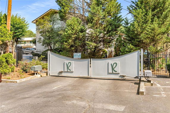 Front view of a gated entrance with a security gate and surrounding trees.