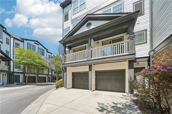 Front view of a multi-story building with a balcony and double garage.