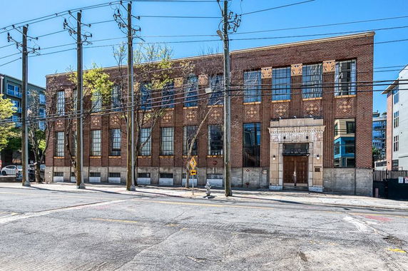 Front view of a multi-story brick building with large windows and a central entrance.