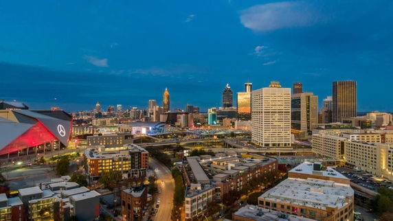 Panoramic view of a city skyline with modern buildings and roads at dusk.
