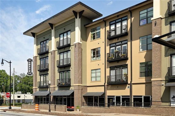 Front view of a multi-story apartment building with balconies and large windows.