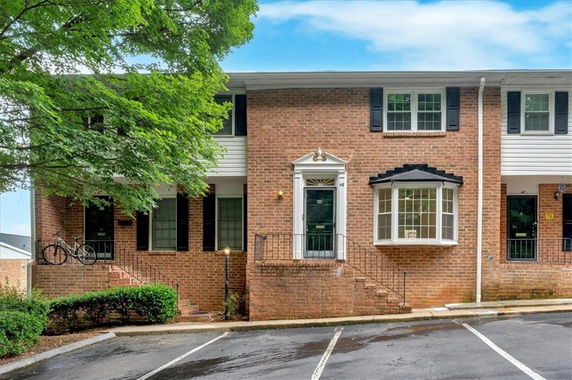 Front view of a brick two-story townhouse with black shutters and steps leading to the entrance.