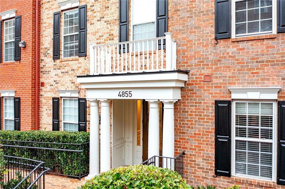 Front view of a brick building with white columns and black window shutters.