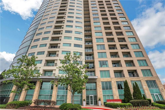 Front view of a high-rise building with many windows and a rounded corner.