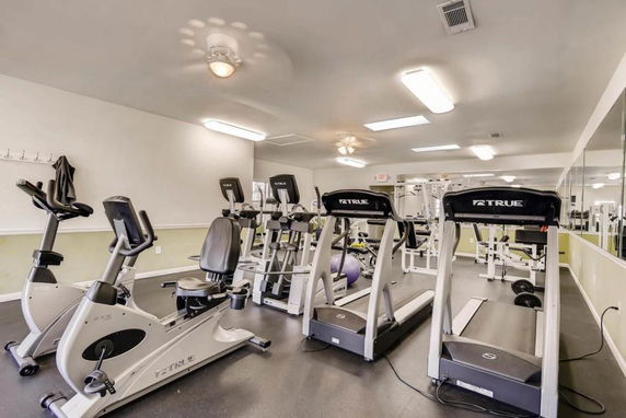 Room with various gym equipment including treadmills and exercise bikes.