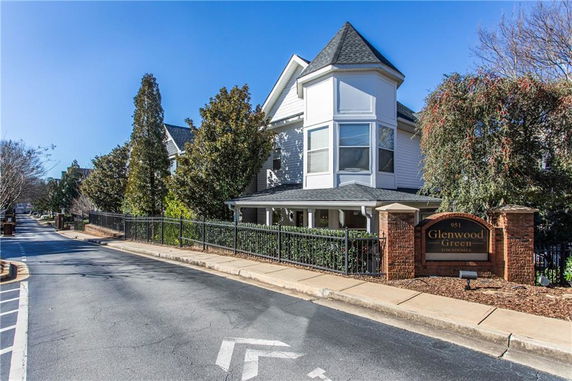 Front view of a multi-story townhouse with a prominent turret and fenced yard.