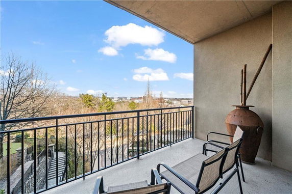 Balcony with metal railing and two chairs overlooking a scenic outdoor area.