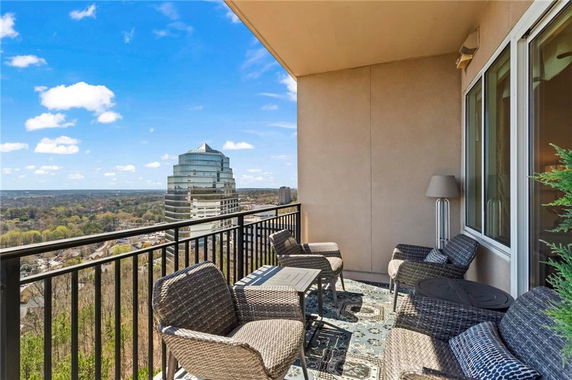 View from a balcony overlooking a cityscape with a modern high-rise building in the distance.