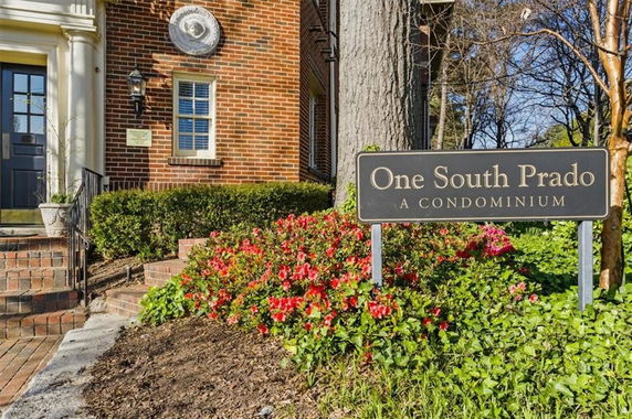 Front view of a brick condominium entrance with a sign reading 'One South Prado A Condominium'.