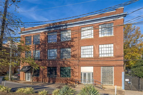 Front view of a three-story brick building with large windows.