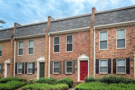 Front view of a two-story brick townhouse with a red door.