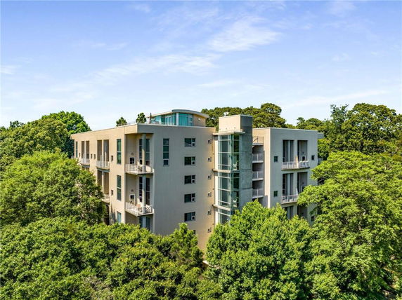 Front view of a multi-story apartment building surrounded by trees.