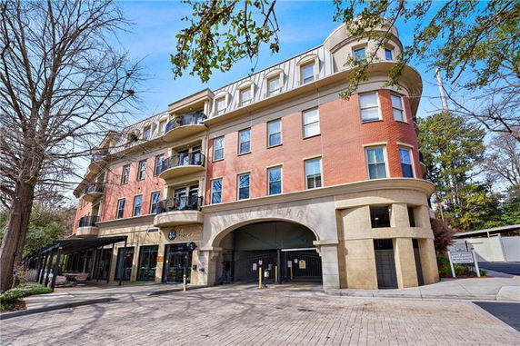 Front view of a multi-story building with balconies and arched entrance.