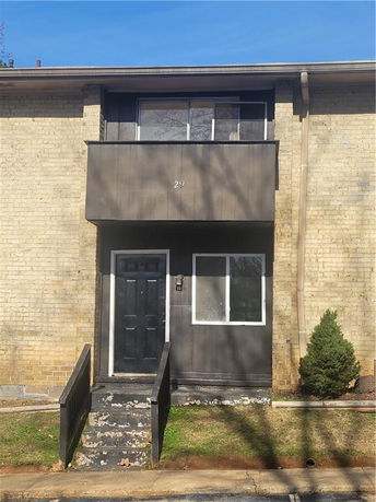 Front view of a two-story building with a dark front door and window, featuring a balcony above.