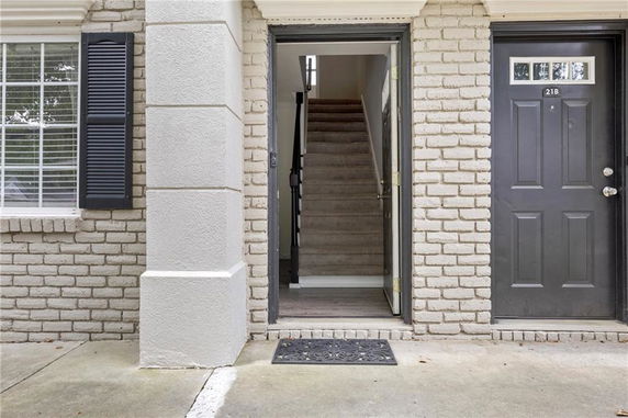 Front view of a building entrance with a brick exterior and nearby staircase.