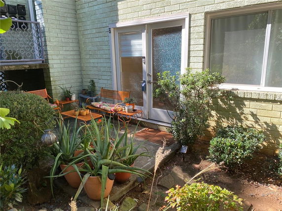 Front view of a building entrance with a small patio area and plants.