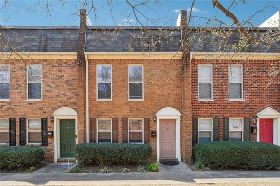 Front view of a townhouse with a brick facade and different colored doors.