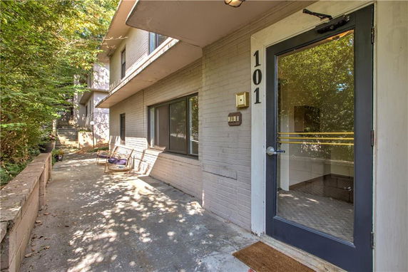 Front view of a two-story building with an outdoor seating area and a glass door entrance.