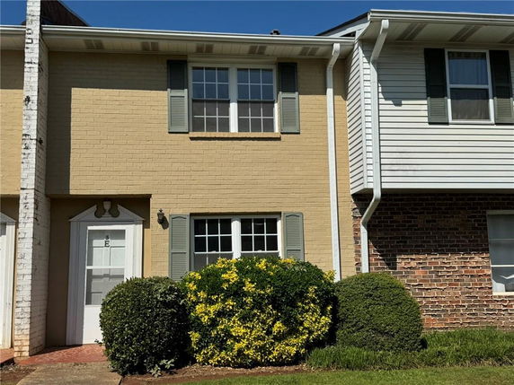 Front view of a two-story townhouse with yellow brick and green shutters.