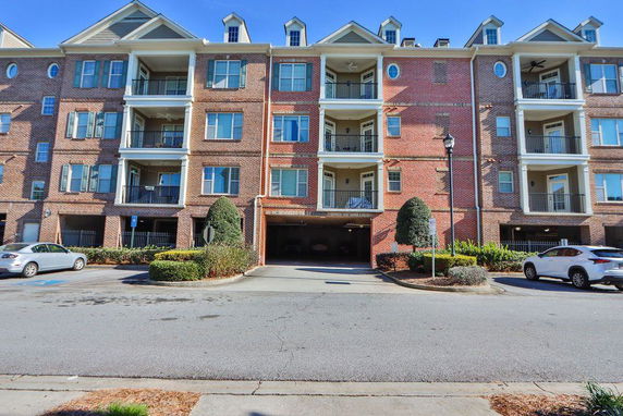 Front view of a multi-story residential building with balconies and brick exterior.