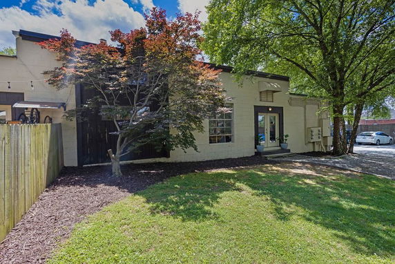 Front view of a single-story building with trees and a small patio area at the entrance.