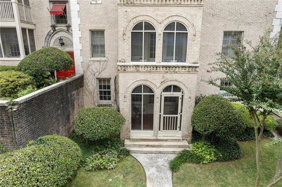 Front view of a two-story building with arched windows and a garden path leading to the entrance.